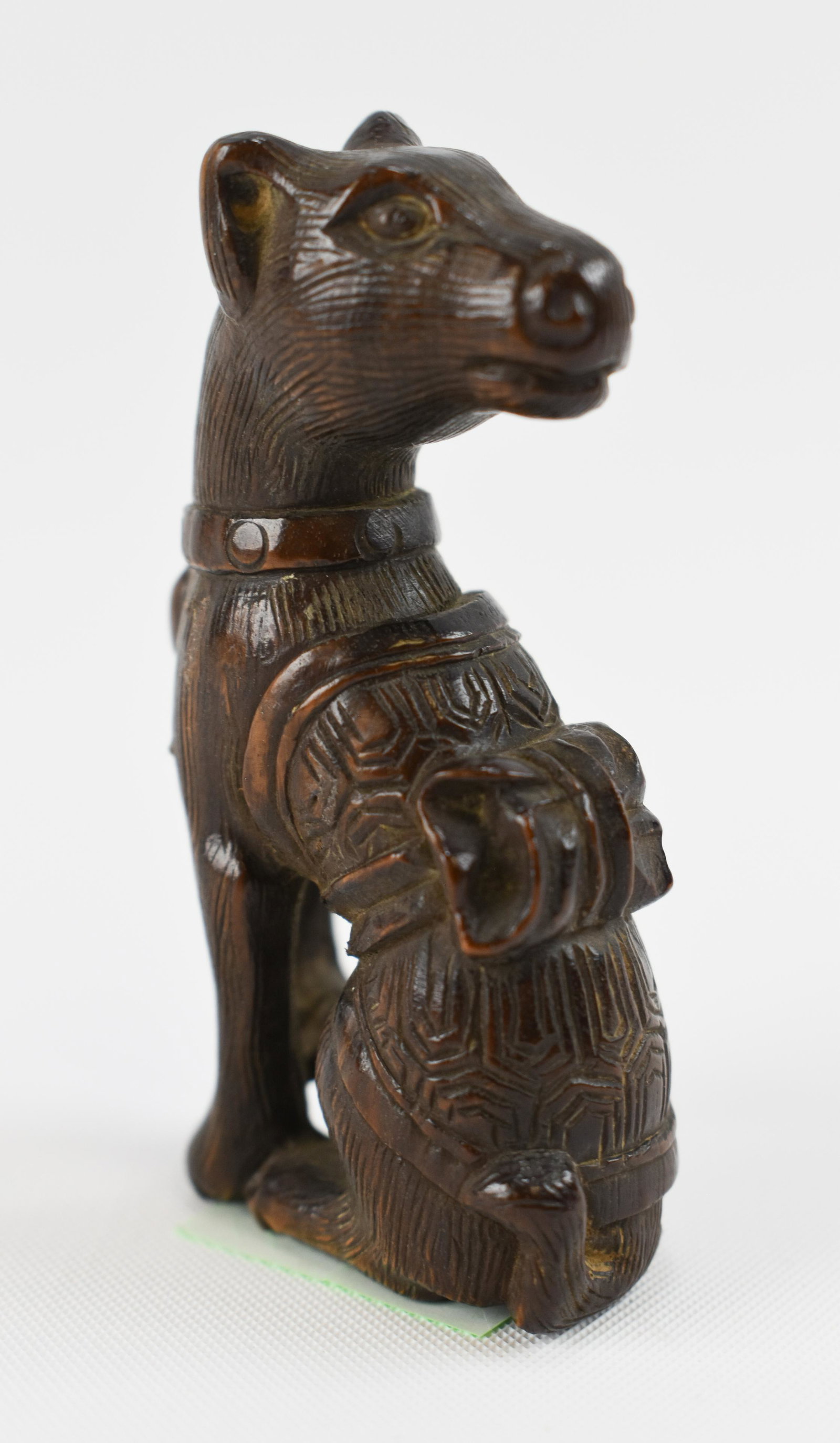 Wood Netsuke of a Dog: Japanese, 20th Century Seated, with the head turned to the back, wearing a small blanket incised with a cell-diaper motif; signed (illegible). Height 2 1/4"