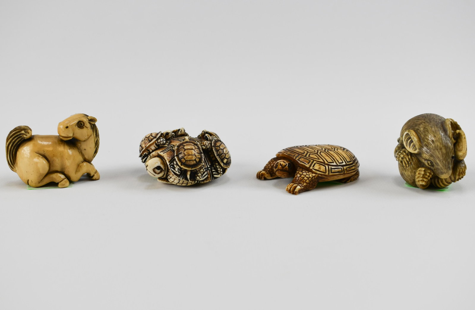 Four Carved Ivory Commercial Netsuke: Hong Kong, 20th Century Including most animal subjects: a recumbent pony, a turtle, an adult turtle with five young, and a coiled rat. Average length: 1 3/4"