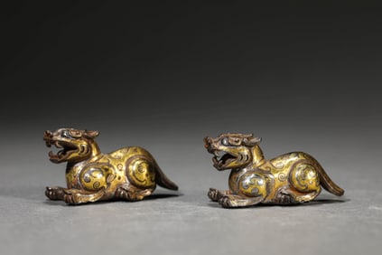 A PAIR OF GOLD AND SILVER-INLAID MYTHICAL BEASTS