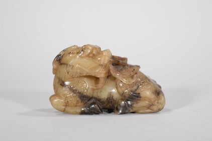 A STAINED JADE 'BEAST CARRYING BOOKS' FIGURE