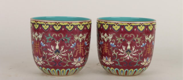 A PAIR OF RED-GROUND FAMILLE ROSE 'INTERLOCKING FLOWERS AND SHOU' CUPS