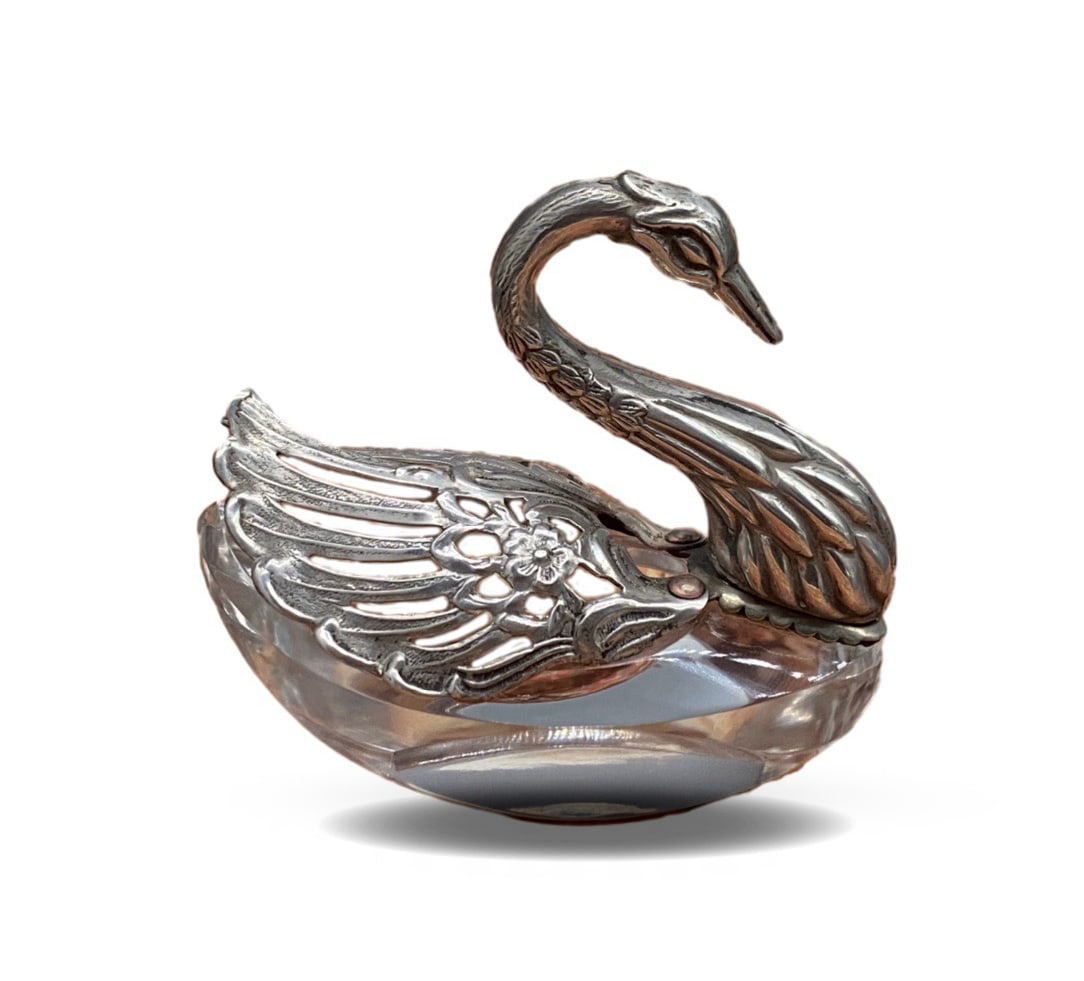 A SMALL CRYSTAL GLASS JAR IN THE SHAPE OF A SILVER SWAN: A SMALL CRYSTAL GLASS JAR IN THE SHAPE OF A SILVER SWAN Dimensions: Weight: 99.0 g. Height 7.0 cm (2.76 in) x Length 8.0 cm (3.15 in) x Width 4.0 cm (1.57 in). All measurements are approximate. Descri