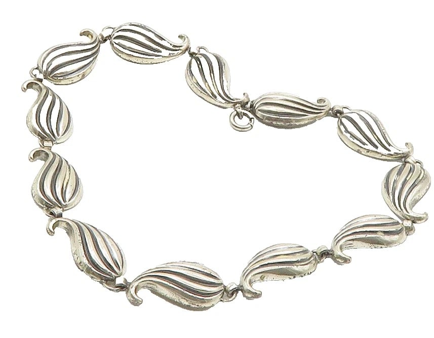 SILVER LINK BRACELET: SILVER LINK BRACELET Description: A silver link bracelet formed from repeating ribbed oval links with clasp. The photographs show the bracelet laid out and a close detail of the link construction.