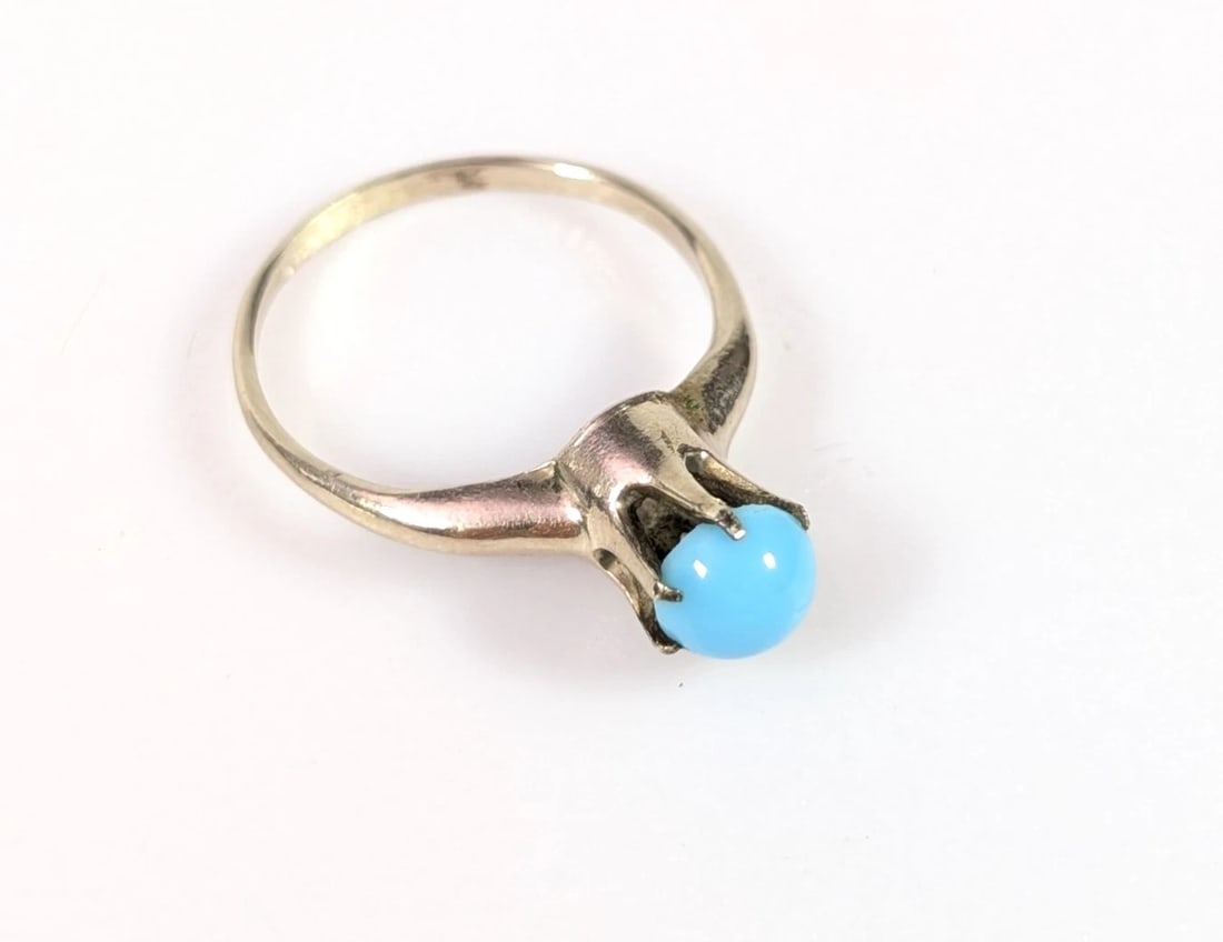 TURQUOISE-SET RING: TURQUOISE-SET RING Description: A ring set with a turquoise-colored cabochon in a simple raised mount. The images show the ring from side and top views.