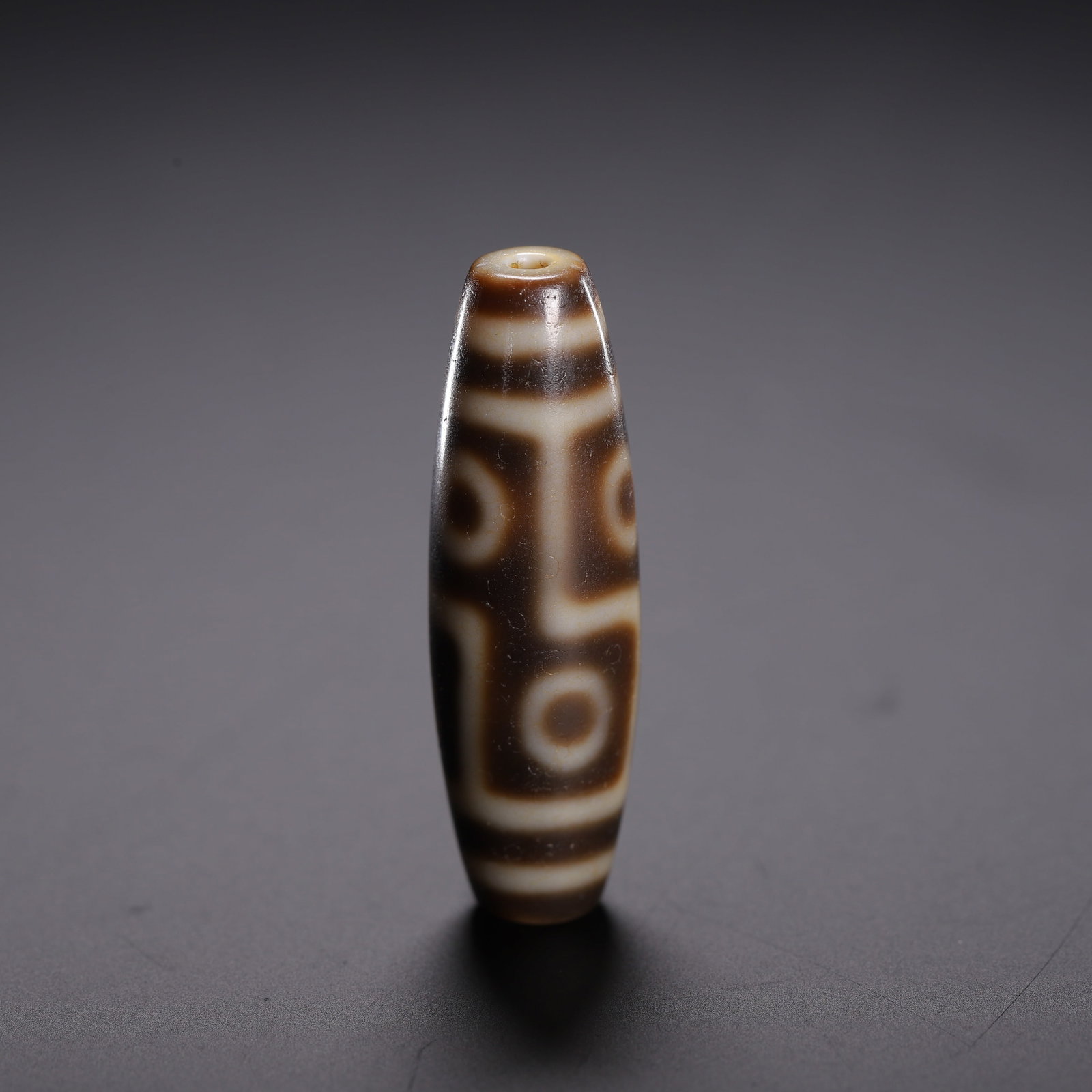 A DZI BEAD: A DZI BEAD Dimensions: Dimensions: Length: 3.7 cm (1.46 in.), Width: 1.2 cm (0.47 in.). Weight: 10 g. All measurements are approximate.