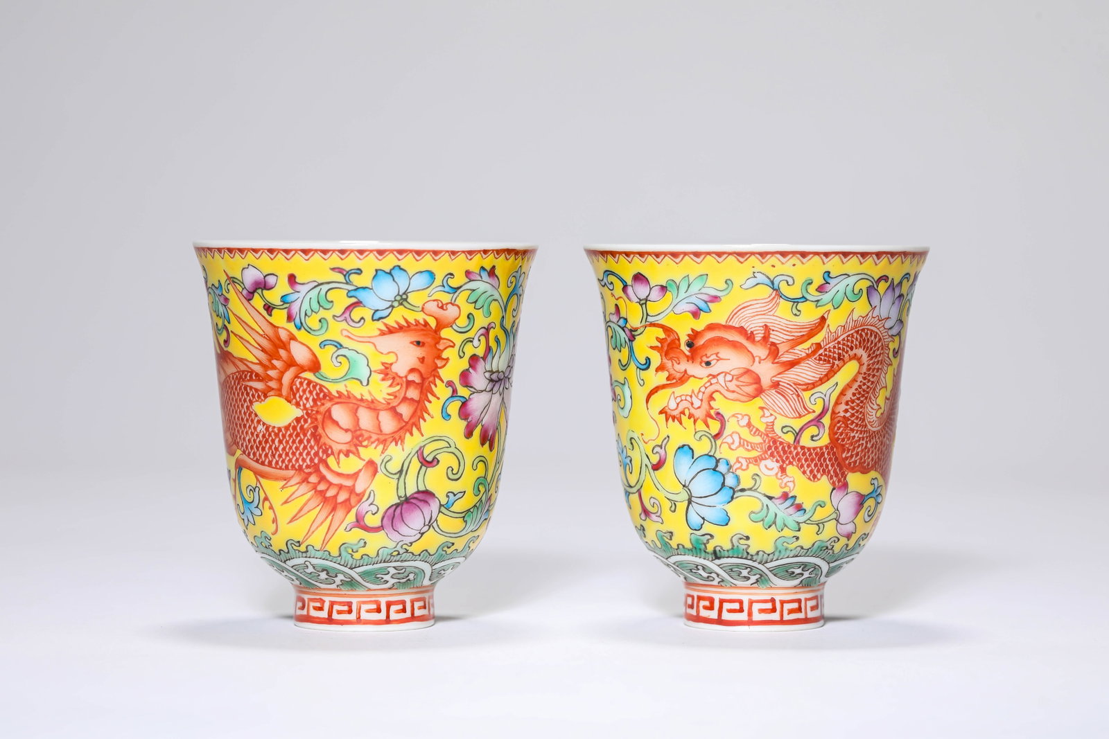 A PAIR OF YELLOW-GROUND FAMILLE ROSE 'DRAGON AND PHOENIX' CUPS: A PAIR OF YELLOW-GROUND FAMILLE ROSE 'DRAGON AND PHOENIX' CUPS Dimensions: Dimensions: Width: 6 cm (2.36 in.), Height: 6.7 cm (2.64 in.). All measurements are approximate.