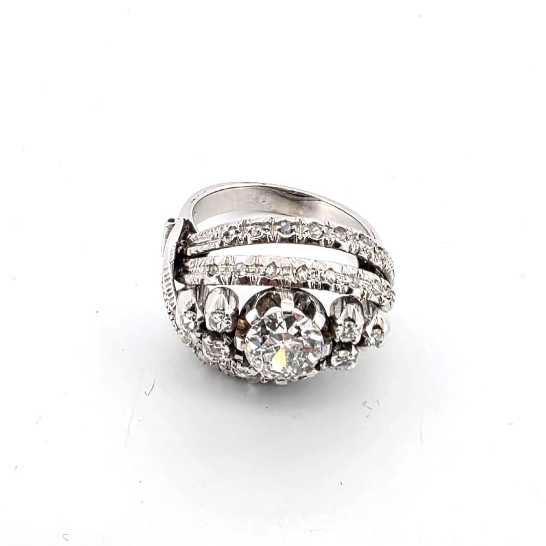 40' RING IN 18KT WHITE GOLD: 40' RING IN 18KT WHITE GOLD Description: The composition presents an elegant diamond ring displayed against a clean white background, emphasizing its sculptural form and brilliant reflective surfaces.