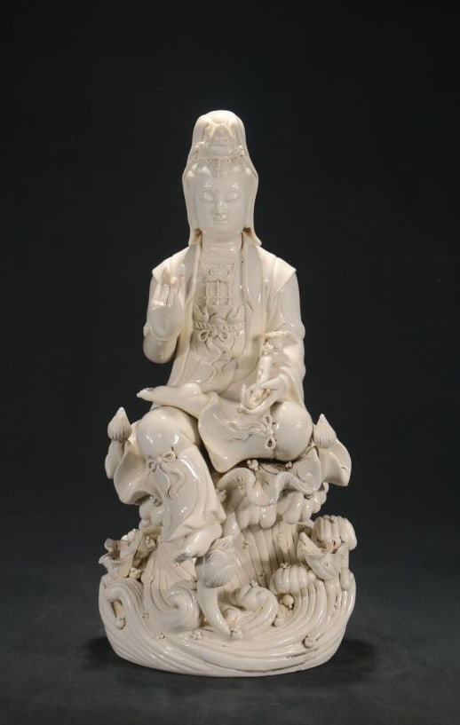 A DEHUA WHITE-GLAZED 'HE CHAOZONG' MARK SEATED GUANYIN WITH WATER MOON AND RUYI: A DEHUA WHITE-GLAZED 'HE CHAOZONG' MARK SEATED GUANYIN WITH WATER MOON AND RUYI Dimensions: Height: 44.5 cm (17.52 in.), Width: 21 cm (8.27 in.). All measurements are approximate.