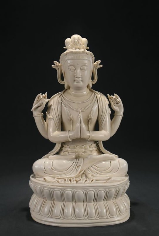 A DEHUA WHITE-GLAZED 'HE CHAOZONG' MARK FOUR-ARMED GUANYIN: A DEHUA WHITE-GLAZED 'HE CHAOZONG' MARK FOUR-ARMED GUANYIN Dimensions: Height: 39 cm (15.35 in.), Width: 23 cm (9.06 in.). All measurements are approximate.