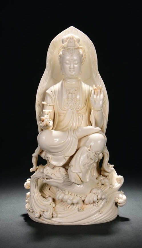 A DEHUA WHITE-GLAZED SEATED GUANYIN ON AO FISH: A DEHUA WHITE-GLAZED SEATED GUANYIN ON AO FISH Dimensions: Height: 44 cm (17.32 in.), Width: 23 cm (9.06 in.). All measurements are approximate.
