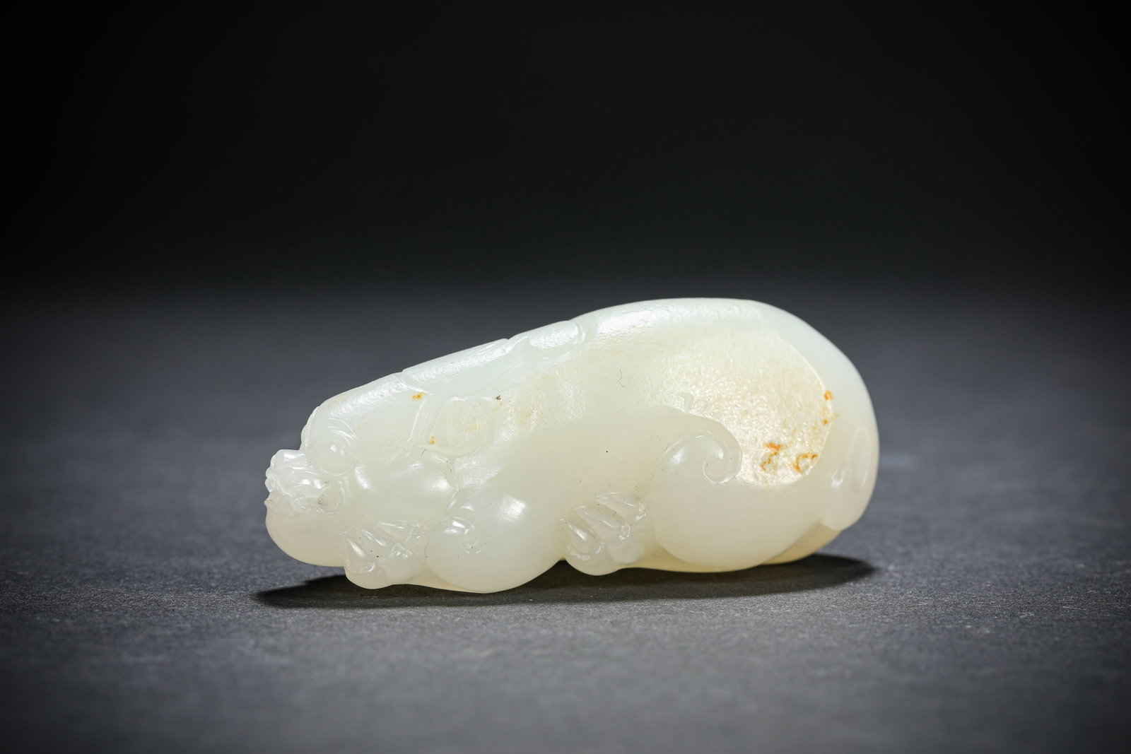 A JADE CARVED AUSPICIOUS BEAST: A JADE CARVED AUSPICIOUS BEAST Dimensions: Length: 6.6 cm (2.60 in.), Width: 2.5 cm (0.98 in.), Height: 2.9 cm (1.14 in.). All measurements are approximate.