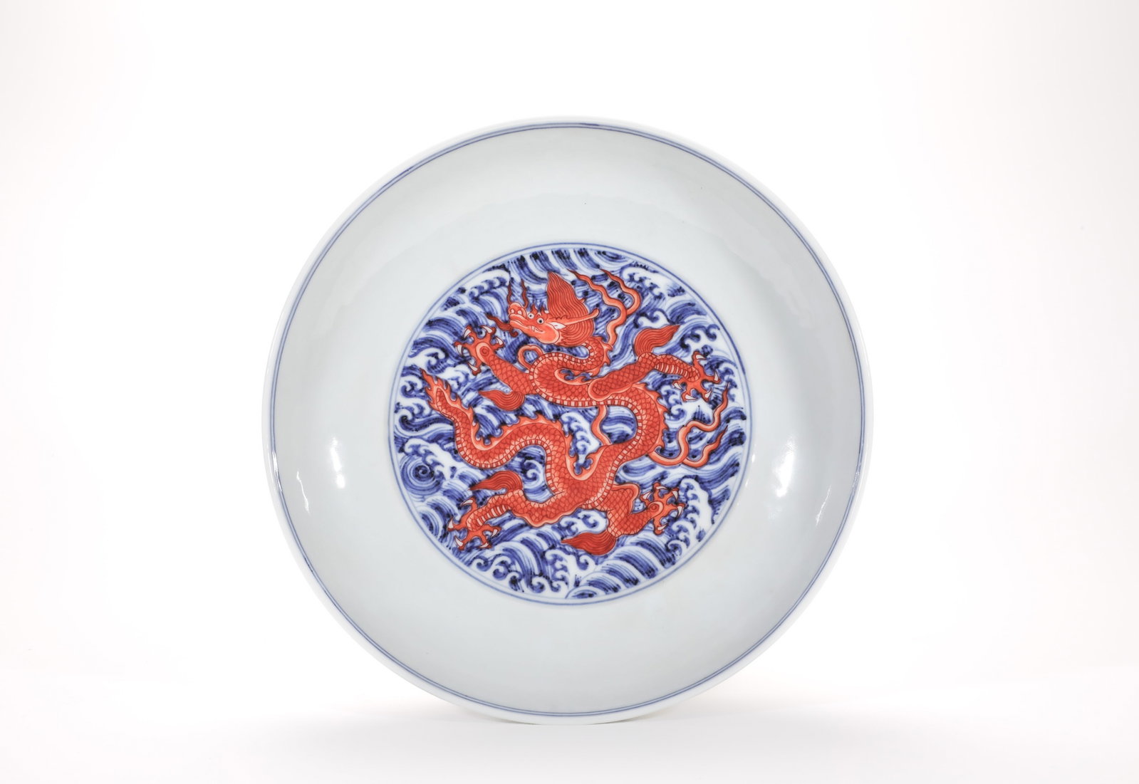 A BLUE AND WHITE AND IRON-RED 'WAVES AND DRAGON' DISH: A BLUE AND WHITE AND IRON-RED 'WAVES AND DRAGON' DISH Dimensions: Length: 22 cm (8.66 in.), Width: 22 cm (8.66 in.), Height: 5 cm (1.97 in.). All measurements are approximate.