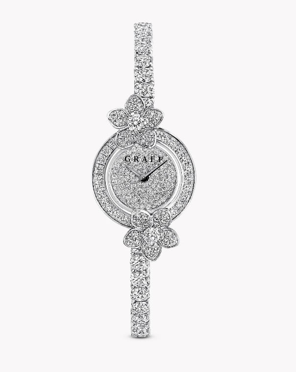 WILD FLOWER DIAMOND WRISTWATCH: WILD FLOWER DIAMOND WRISTWATCH Description: The elegant and distinctive 18K white gold Wild Flower watch features two diamond flowers connected by a circle of closely set diamonds, paired with a round