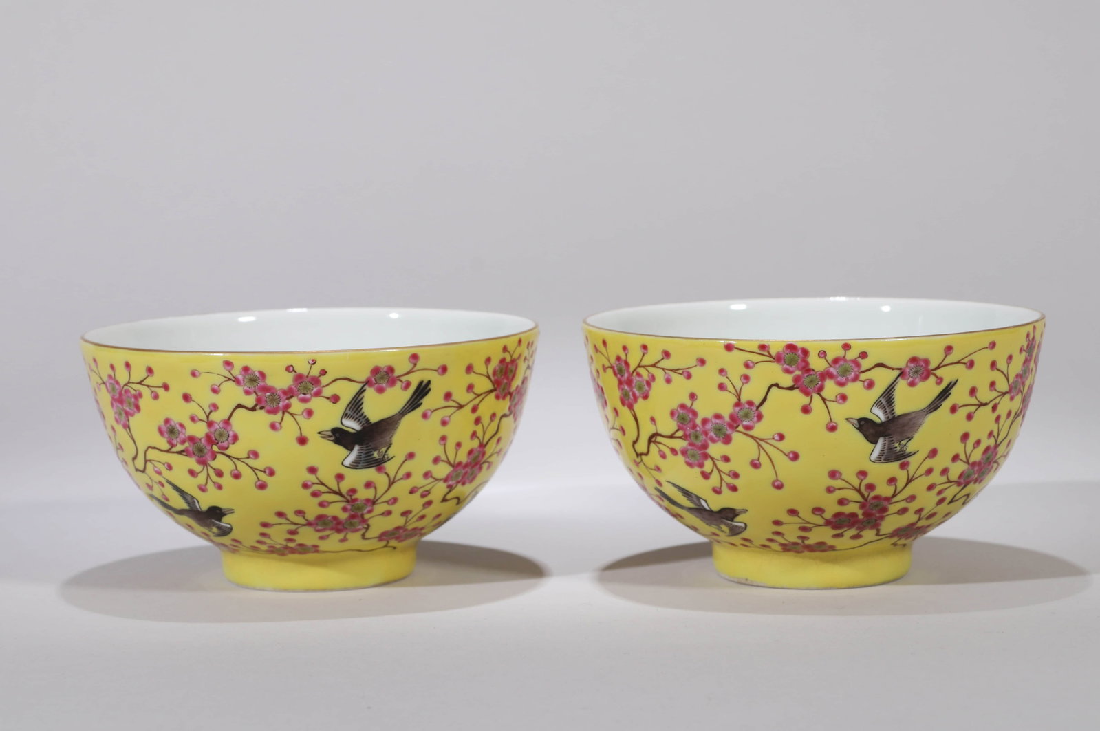 A PAIR OF YELLOW-GROUND FAMILLE ROSE 'FLOWERS AND BIRDS' BOWLS: A PAIR OF YELLOW-GROUND FAMILLE ROSE 'FLOWERS AND BIRDS' BOWLS Dimensions: Diameter: 11 cm (4.33 in.), Height: 6 cm (2.36 in.). All measurements are approximate.