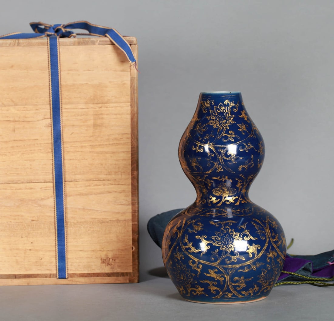 A BLUE-GLAZED AND GILT 'INTERLOCKING FLOWERS' GOURD VASE: A BLUE-GLAZED AND GILT 'INTERLOCKING FLOWERS' GOURD VASE Dimensions: Height: 22 cm (8.66 in.). All measurements are approximate.