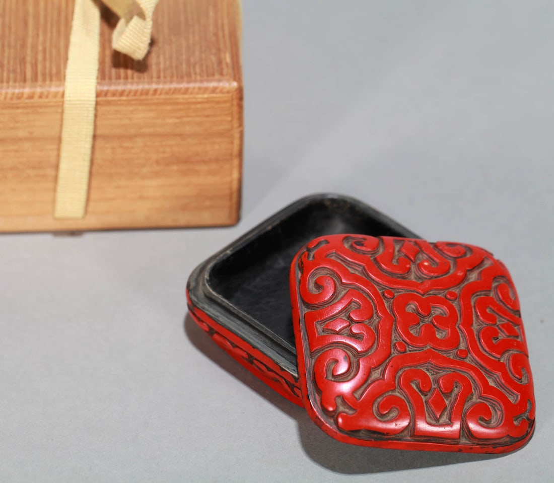 A CARVED CINNABAR LACQUER 'FLOWERS' COVERED BOX: A CARVED CINNABAR LACQUER 'FLOWERS' COVERED BOX Dimensions: Length: 7 cm (2.76 in.), Width: 7 cm (2.76 in.), Height: 3 cm (1.18 in.). All measurements are approximate.