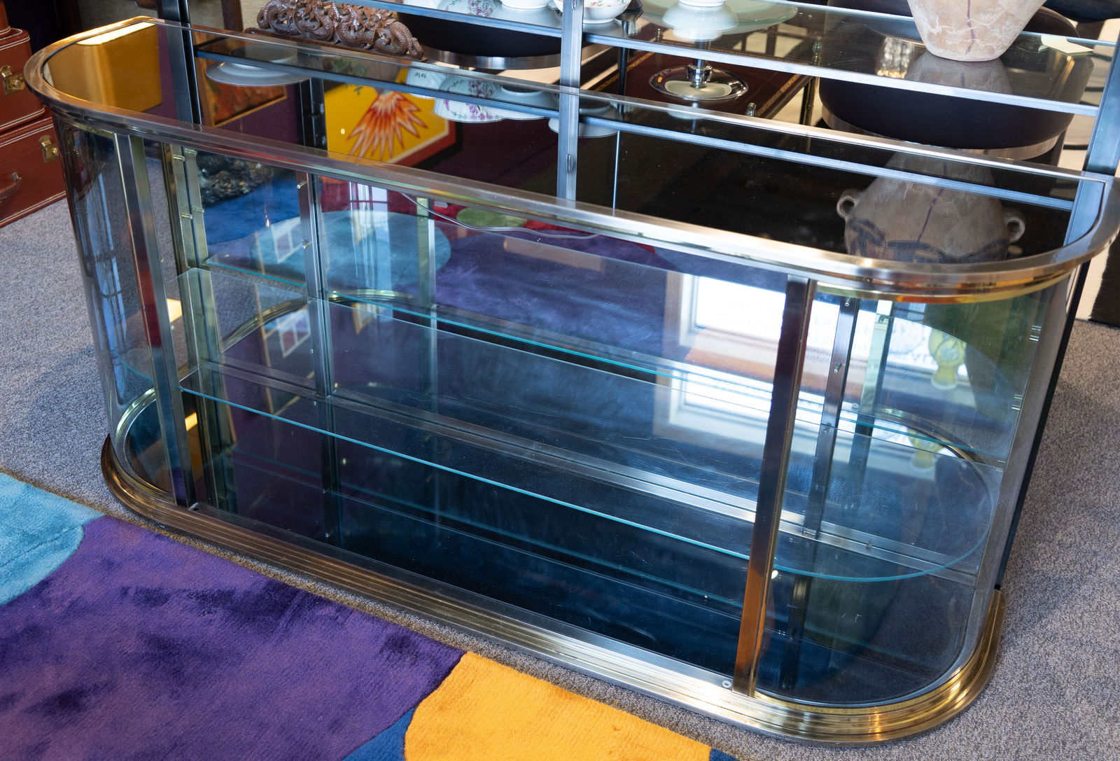 Mastercraft-Style Smoked Glass Bar: A Mastercraft-style smoked glass bar. The glass cabinet features curving sides with two front glass doors opening to reveal two interior shelves. Size: 30H x 65W x 18.5D. The inside of the cabinet has