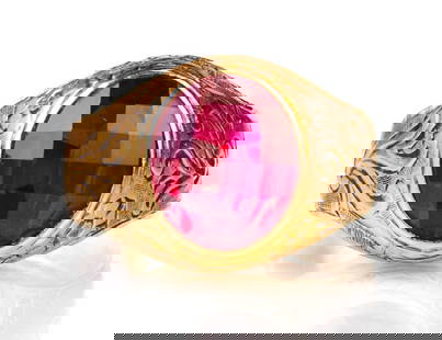 14k Synthetic Ruby Ring: 14k yellow gold ring with a bezel set multifaceted oval synthetic ruby, surrounded by carved stylized floral motifs. Ring Size: 10. Markings: no marking but tested for 14k. Total weight: 5 dwt (7.8