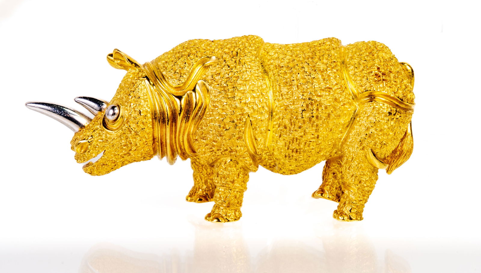 18k Henry Dunay Rhinoceros Brooch: 18k yellow gold and platinumbrooch. The rhinoceros body is a textured finish in 18k yellow gold with the eye and horn of platinum. Designer: Henry Paul Dunay. Measurements: Approximately 2 1/2 inches
