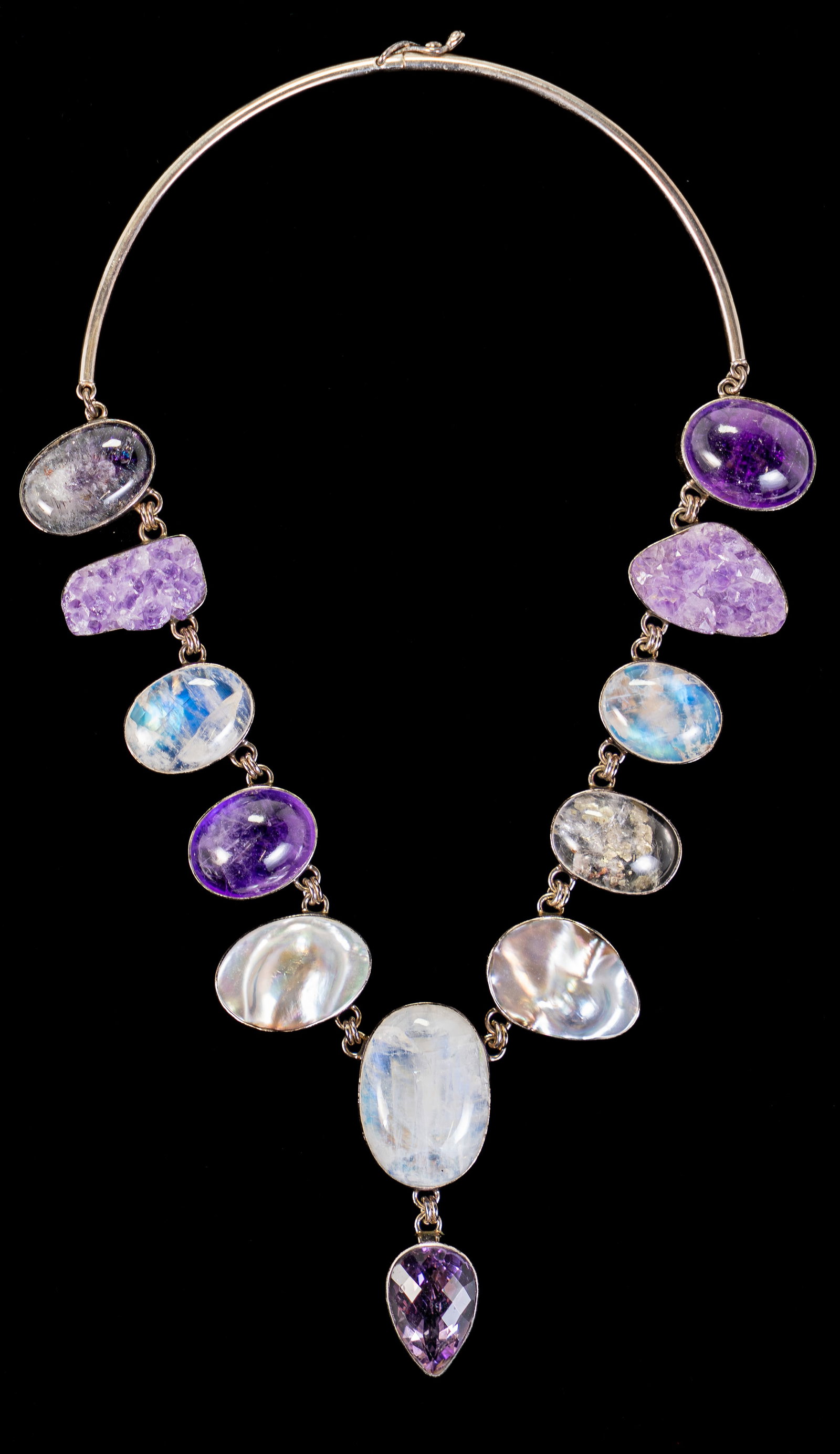 Sterling Silver & Semiprecious Stones Necklace: Sterling silver necklace with eleven (11) stations bezel set with semi-precious stones of various shapes and sizes, including rose quartz, moonstones, mother of pearl, and ending with a multi-faceted 