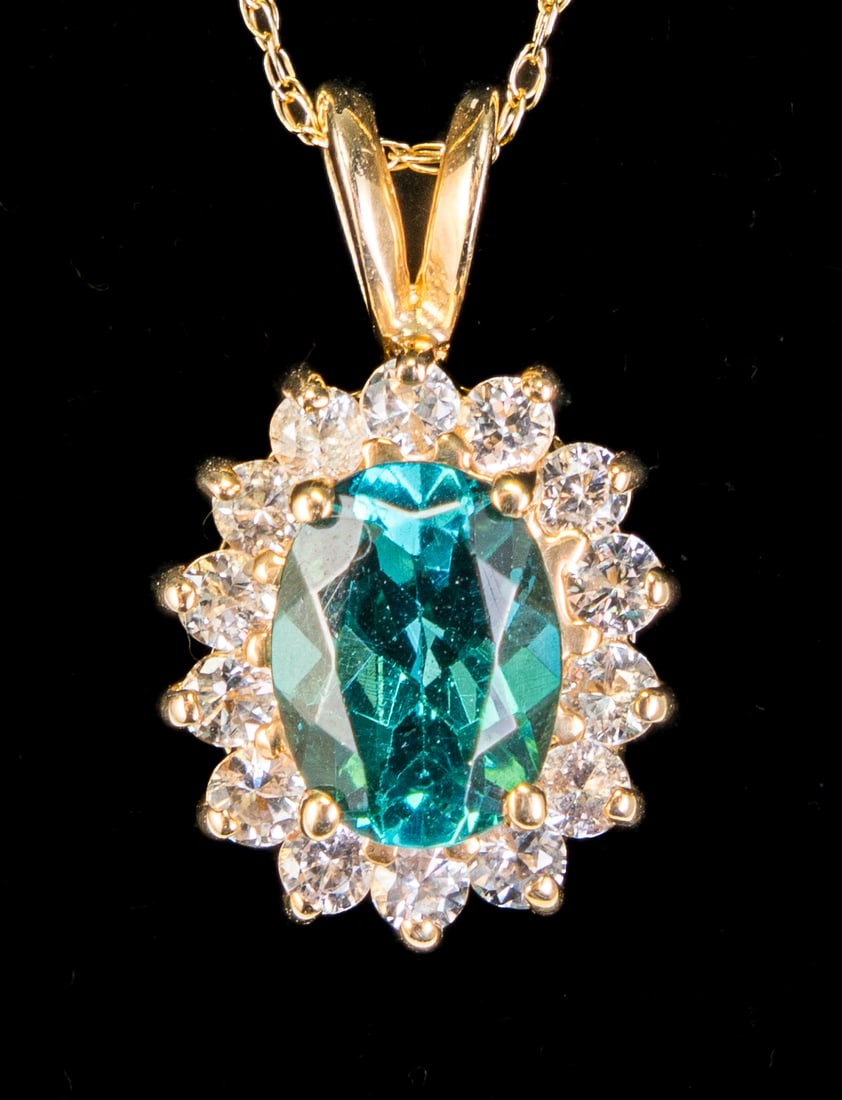 14k Gold & Tourmaline Necklace: 14k yellow gold and tourmaline necklace, with a pendant showcasing an oval cut teal color tourmaline, surrounded by a melee diamond halo, on a very thing chain ending with a spring ring. Measurements: