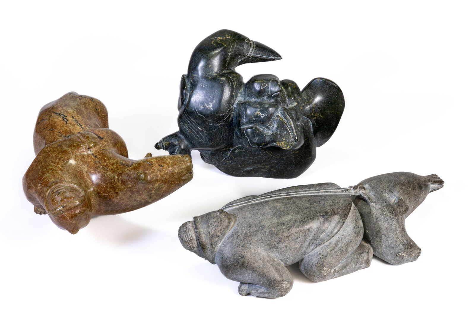 Three (3) Vintage Inuit Sculptures Temela Ilisituk Munamee: Three Inuit stone sculptures purchased at the Alaska Shop in 1984-85. The brown stone is titled Bear Transformation by Takealook Temala measuring 14 in. long, the second one is Alcid With Young attrib