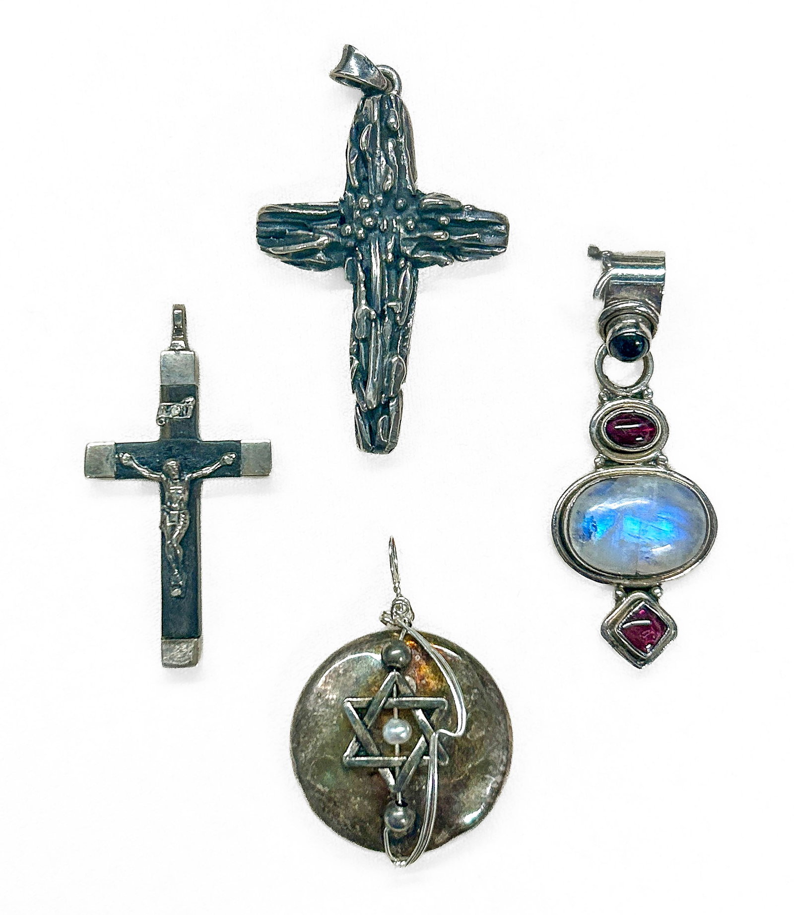Sterling Silver Pendants: Four (4) sterling silver pendants: Star of David with cultured pearl, garnet/moonstone pendant, textured silver cross, and silver/wood cross. Small cross and moonstone marked "Sterling Silver" and