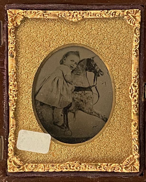 [AMBROTYPE] LITTLE GIRL ON ROCKING HORSE: Anonymous [Little Girl on Rocking Horse] Sixteenth plate ambrotype. Ruby glass; gutta perch case. 1857 Additional images and detailed condition reports are available upon request.