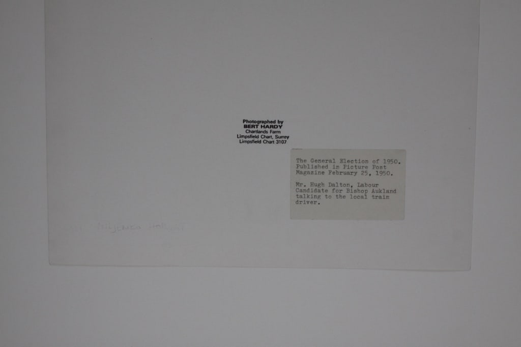 HARDY, BERT. GENERAL ELECTION, HUGH DALTON: Hardy, Bert. THE GENERAL ELECTION OF 1950; MR. HUGH DALTON, LABOUR CANDIDATE FOR BISHOP AUKLAND TALKING TO THE LOCAL TRAIN DRIVER. Gelatin silver print in mat. Signed by Hardy in marker on bottom righ