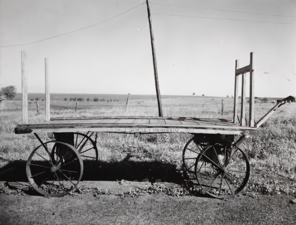 MORRIS, W. DEPOT WAGON, PANAMA, NE. 1947 (1975): MORRIS, Wright. DEPOT WAGON, PANAMA, NEBRASKA (1947). 1975 work proof. Silver print mounted with plastic corner in mat. Print verso titled, dated, marked 'WP'. Print: 4" x 5"; mat: 12.25" x 11.5". Gen