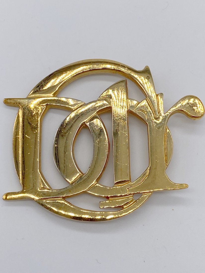 Gold tone Dior Signed Pin: 2.5" gold tone signed Dior pin. Wonderful addition for a collection or also used as a belt buckle. This sale is online only-no public preview or live in house sale will be held. Please ask for additio