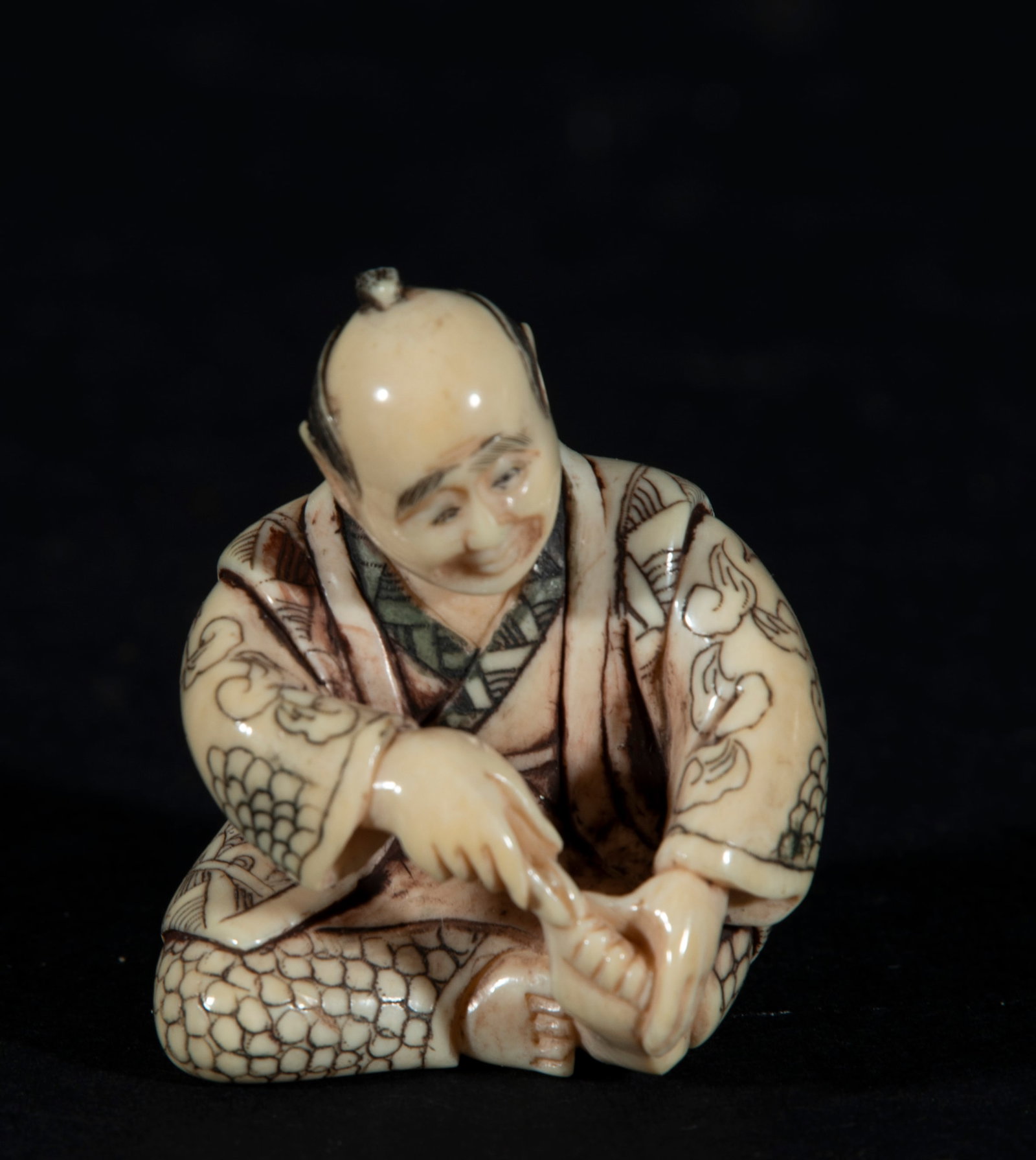 Japanese Netsuke on Mammoth Tusk (Mammuthus primigenius) depicting Old Man Cutting Nails, 19th: With artisan seal, measurements: 4.5 x 3.5 x 3 cm. Provenance: private collection of a lawyer and collector, Barcelona. Acquired in the 60s-70s in Paris.