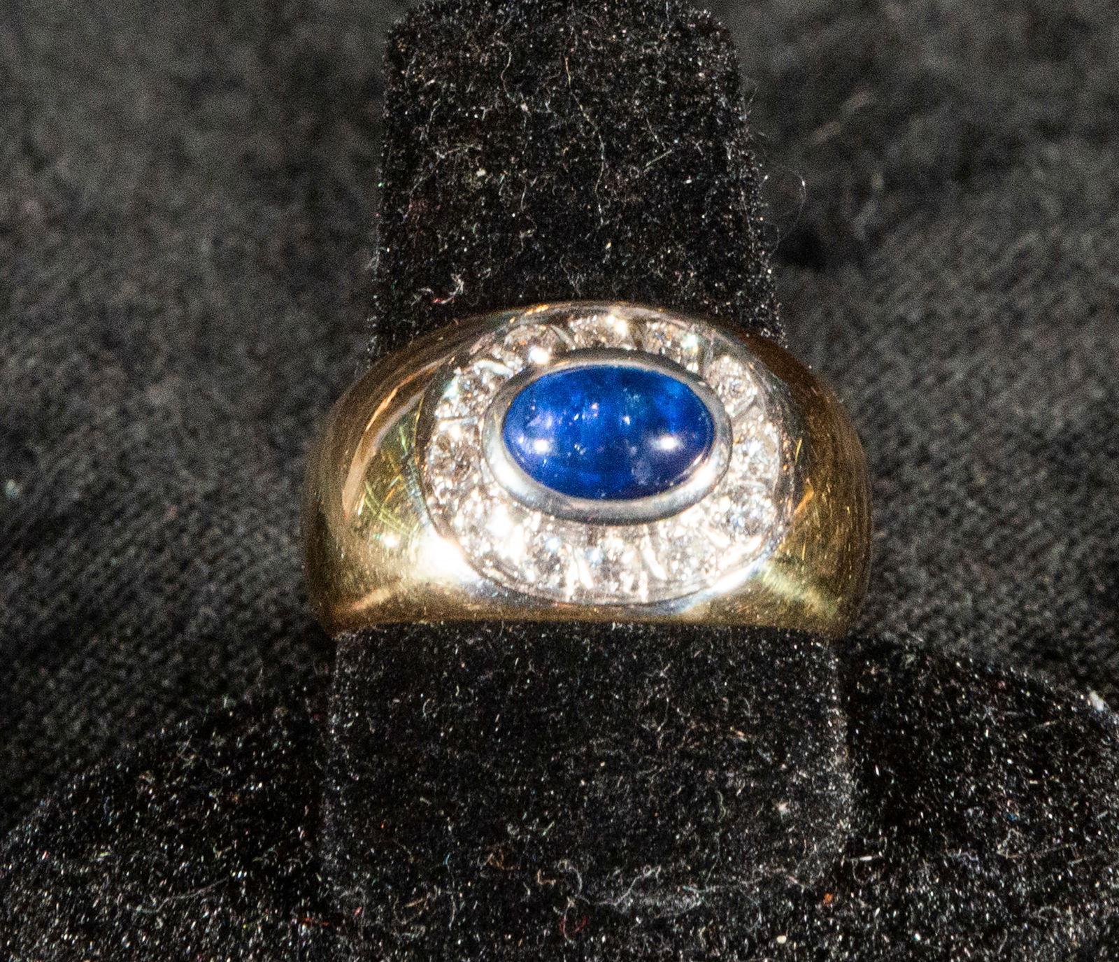 18k yellow gold ring with oval cabochon cut sapphire surrounded by brilliant cut diamonds