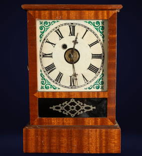 Mantel clock with painted dial. American School. 19th century: Polychrome wood and enameled dial. Dimensions: 30 x 20 x 9 cm. Mantel clock with a rectangular case in grained wood, featuring a circular enameled dial decorated with green motifs at the corners. Meta