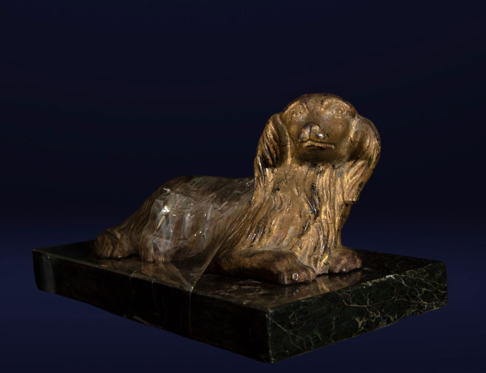 Bronze dog on a marble pedestal. European School. 20th century.: Bronze and marble. Small sculpture depicting an elongated dog resting on a rectangular dark green marble base. The simple modeling, with schematic lines in the coat and features, gives the piece an ex
