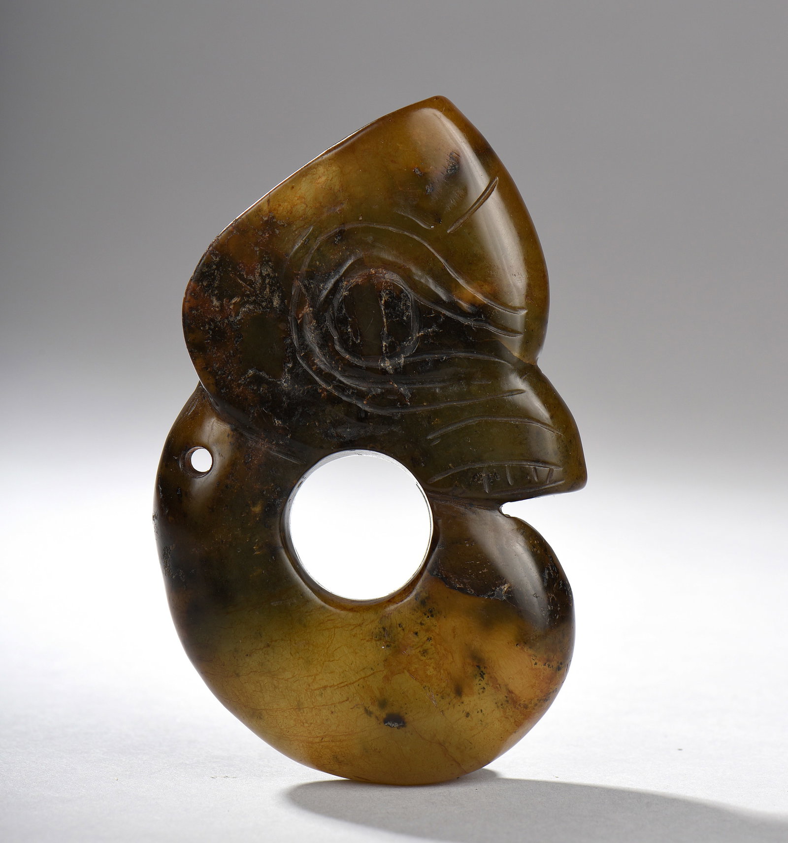 Ornamental element with a bird's head and two holes. Honey amber jade. Porcelain. Neolithic period.: Neolithic period. 10.5 cm.