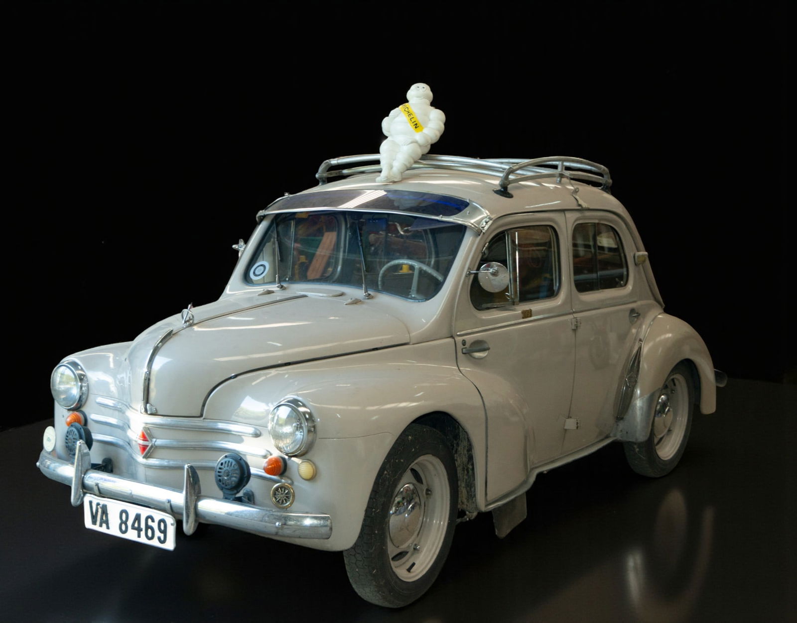 Renault 4CV with Michelin advertising figure.: Classic Renault 4CV, closed body in gray with chrome details. Approximate dimensions: 370 x 150 x 140 cm. An emblematic example of post-war Europe, produced by Renault in the 1950s, featuring a Michel