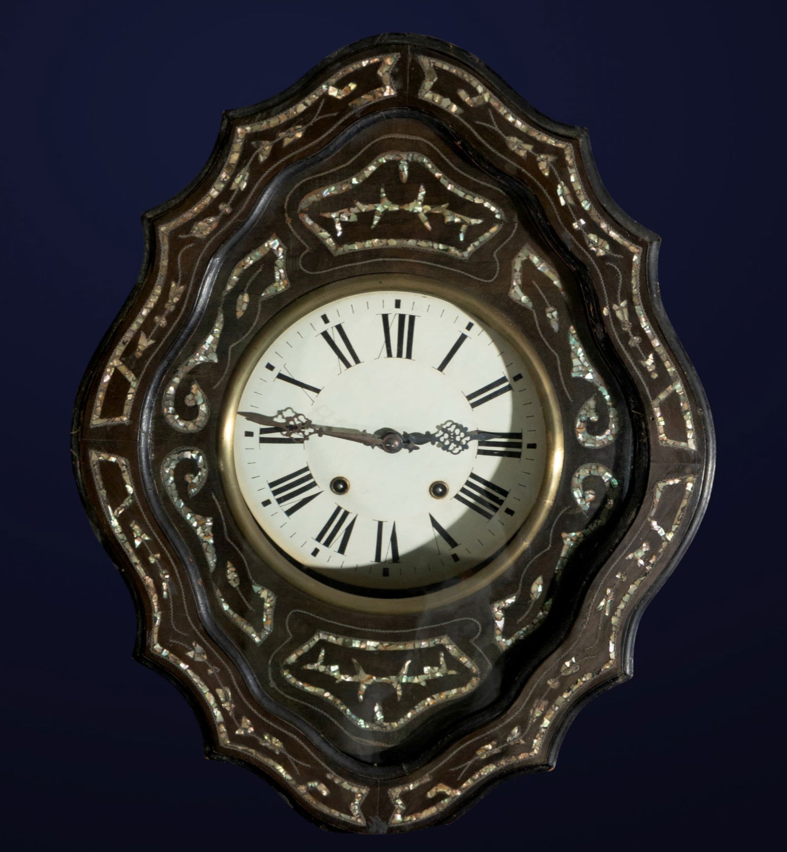 Porthole clock with mother-of-pearl marquetry. French School. 19th century: Ebonized wood with mother-of-pearl marquetry and enameled dial. Dimensions: 62 x 48 x 20 cm. A porthole-style wall clock with a richly carved case decorated with mother-of-pearl marquetry in curviline