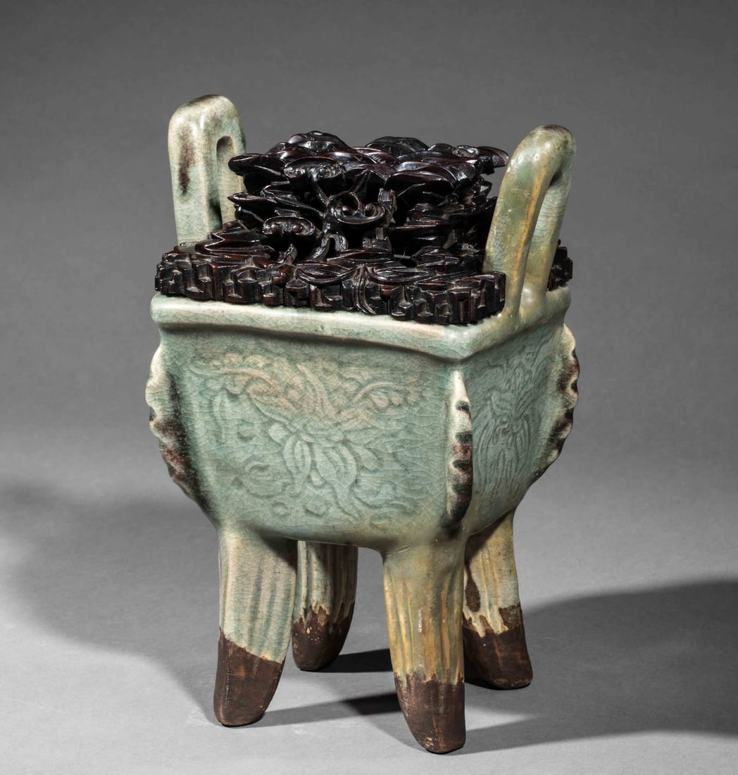 Archaic tusk perfume burner in thick porcelain with floral motifs engraved under a monochrome: Archaic tusk perfume burner in thick porcelain with floral motifs engraved under a monochrome celadon glaze. Wooden lid chiseled with openwork longevity mushrooms. Porcelain. Qing Dynasty. 19th centur