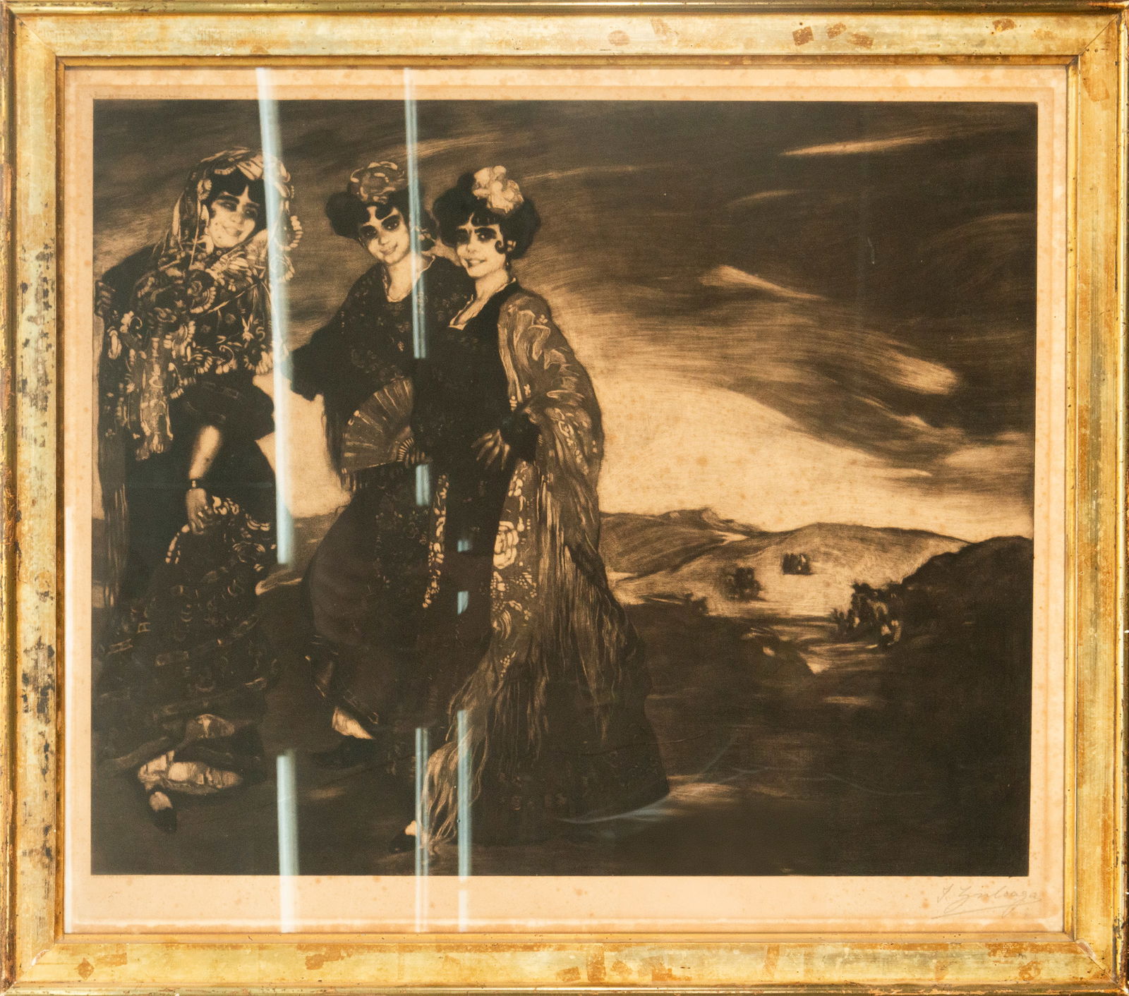 Ignacio Zuloaga. Three Majas. Spanish School. 20th Century. Signed.: Sepia-toned etching on laid paper. Measures 65 x 56 cm. The composition features three female figures adorned with Manila shawls and hair combs, set in a Castilian landscape. The vigorous style, with