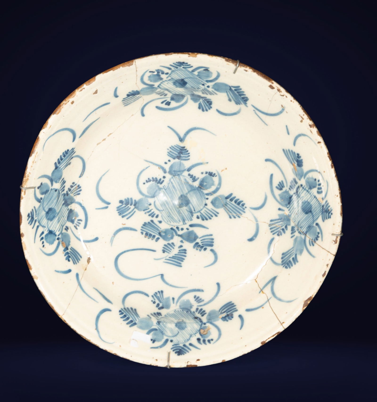 Blue ceramic plate from Triana. Spanish School. 18th century.: Glazed ceramic decorated in cobalt blue on a cream background. Measures 34 x 34 x 7 cm. Floral and geometric motifs arranged symmetrically, characteristic of the Sevillian pottery tradition. A popular