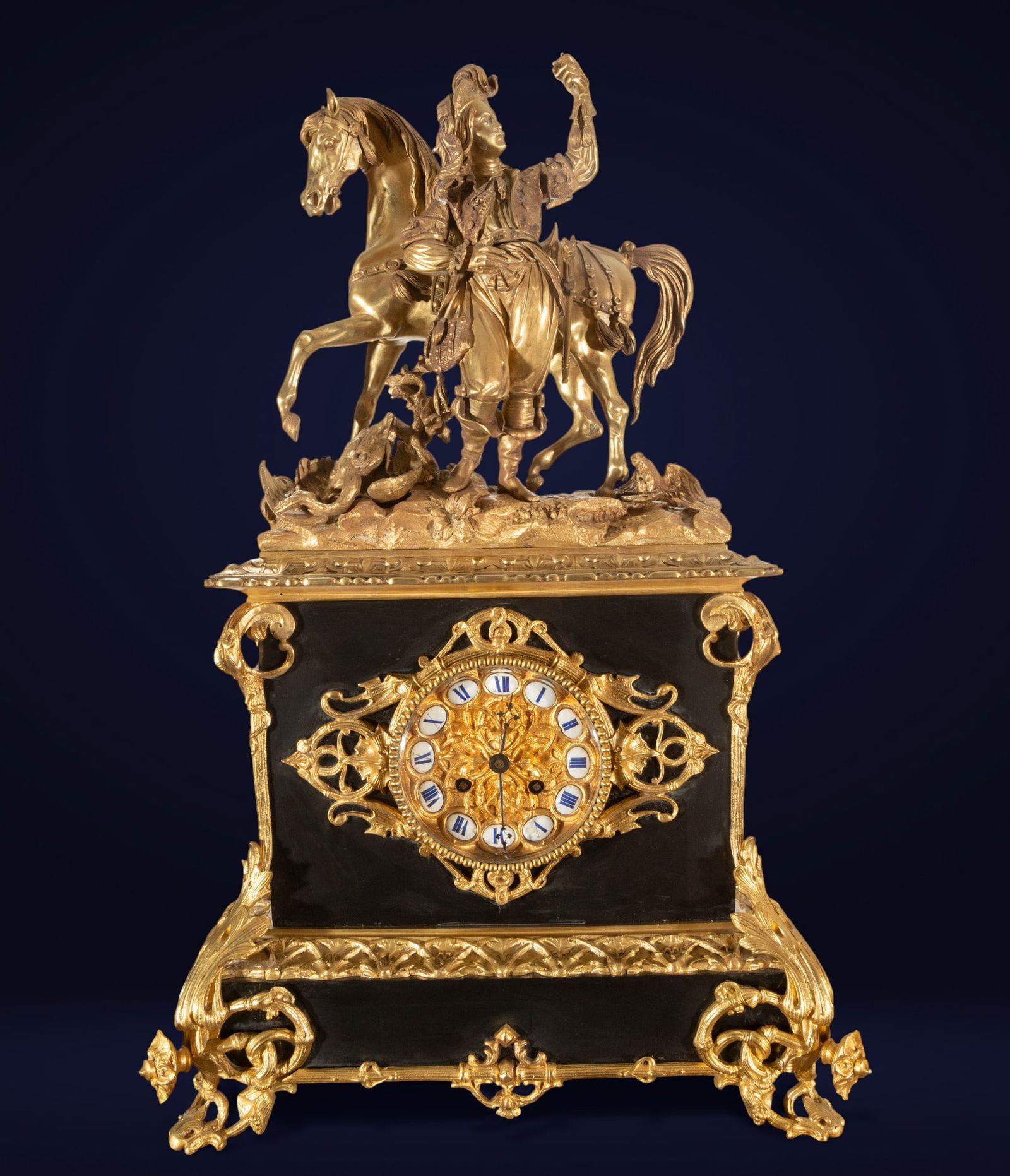 Bronze and marble mantel clock, France, 19th century: Gilt bronze and black marble. Dimensions: 57 × 36 × 16 cm. Louis XV style mantel clock with a rectangular frame and decoration of scrolls and mascarons. A gilt bronze equestrian sculpture group sits