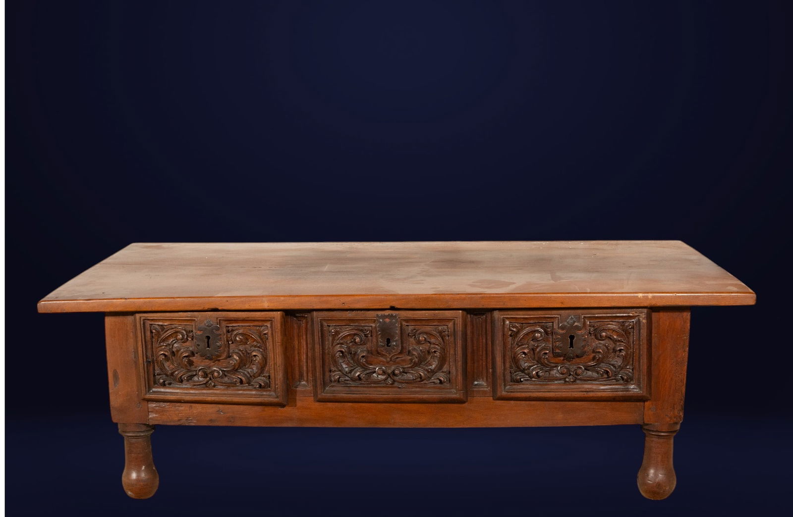 Three-drawer table adapted for the living room. Spanish School. 17th century.: Carved walnut wood with iron fittings. Dimensions: 48 x 148 x 64 cm. 17th-century Spanish table, later adapted as a living room table, with a sturdy structure and a sober rectangular design. The front