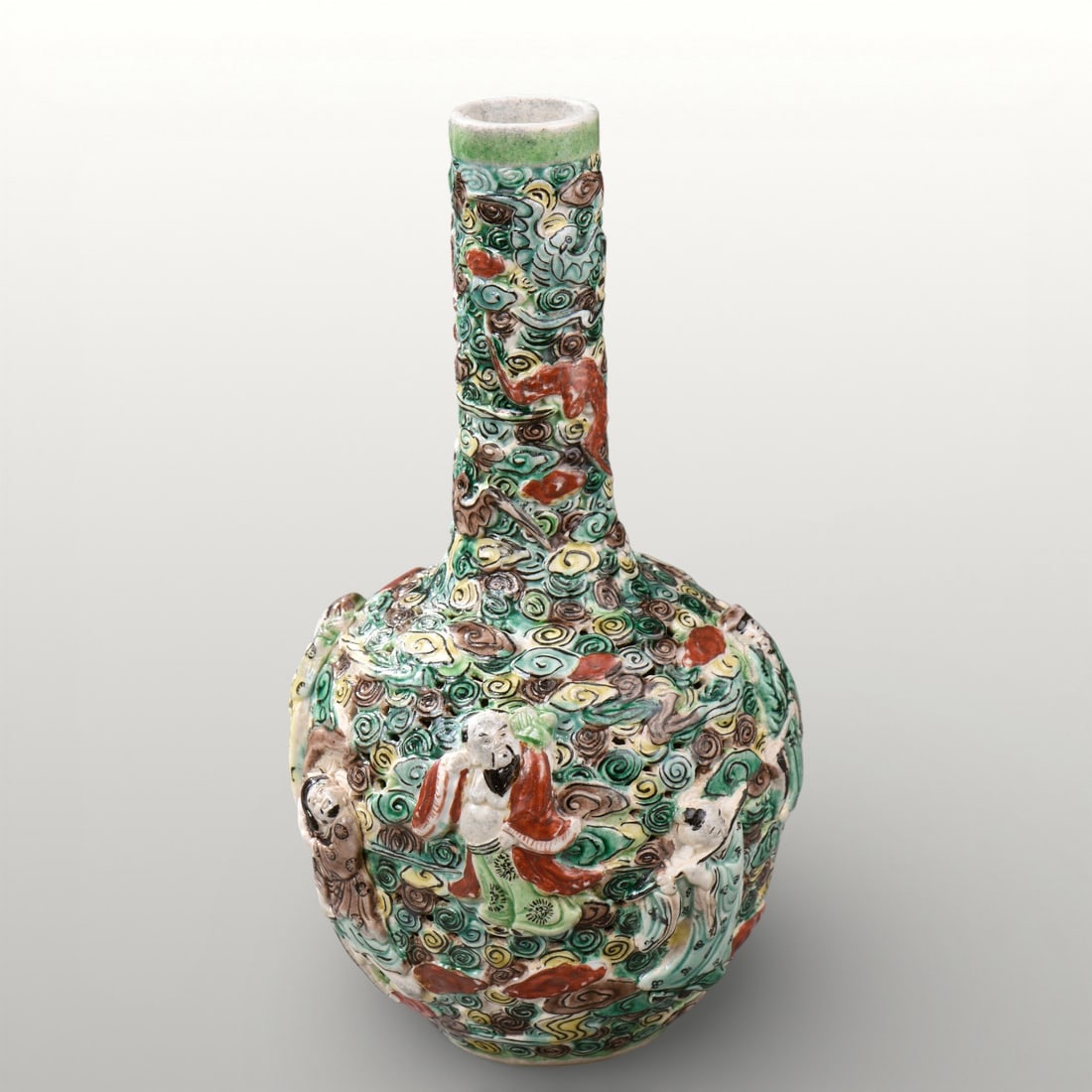 Flacon with embossed lohans, China, Qing Dynasty, 19th Century: Molded porcelain with polychrome glazes. Height 23 cm. Flask with a globular belly and tall cylindrical neck, decorated in relief with lohans figures among tsi clouds. Densely worked surface, with exp