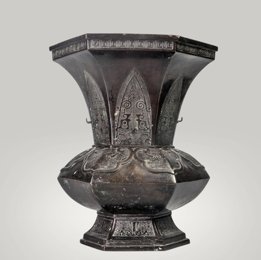 Hexagonal bronze vase of archaic inspiration, Japan, Meiji Period, 19th Century: Bronze. Dimensions: Height 31.5 cm x Mouth diameter 26.5 cm. Hexagonal vessel with a wide, faceted body and a tall, flared neck, constructed from well-defined planes that accentuate its volume and scu