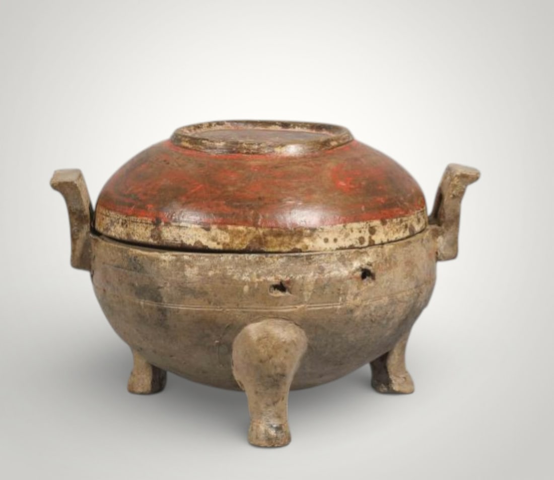 Ding tripod urn with handles, China, Han Dynasty, 2nd century BC. C. - III d. c.: Terracotta with polychrome decoration in red and beige pigments. Measures 23 cm in diameter x 15.4 cm high. Ding-type urn supported on three short, sturdy legs, with a covered globular body and two la