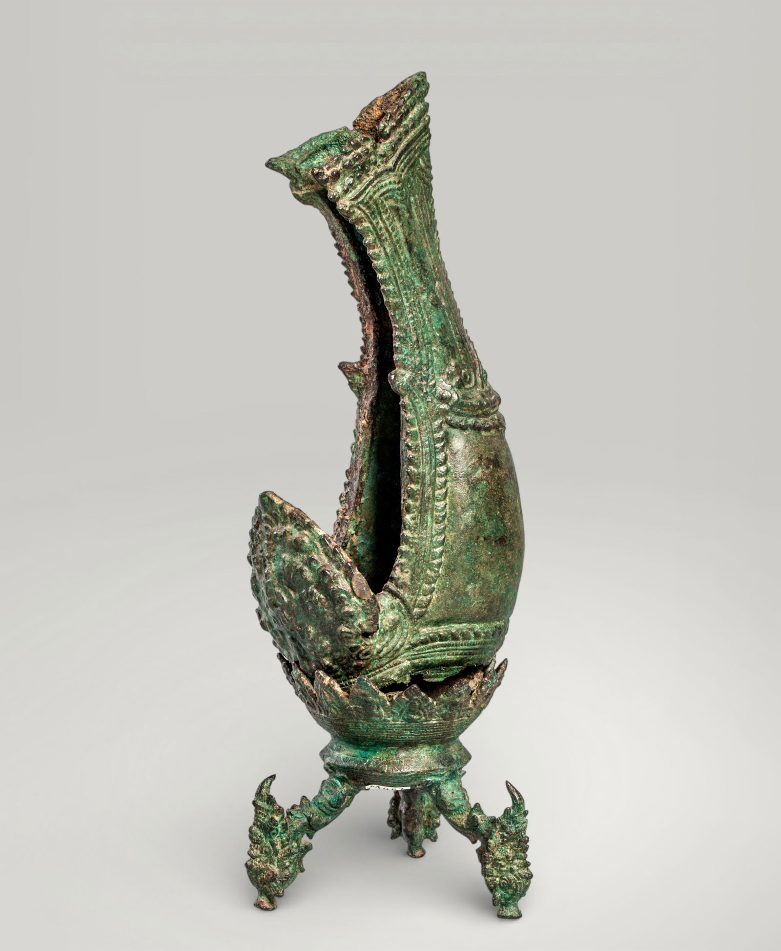 Shankha shell with Garuda. Khmer art. 13th century: Cast bronze with an excavation patina. Height: 29 cm plus a 10 cm base. Shankha shell, one of Vishnu's sacred attributes, mounted on a tripod support surmounted by Garuda heads, a mythological creatur