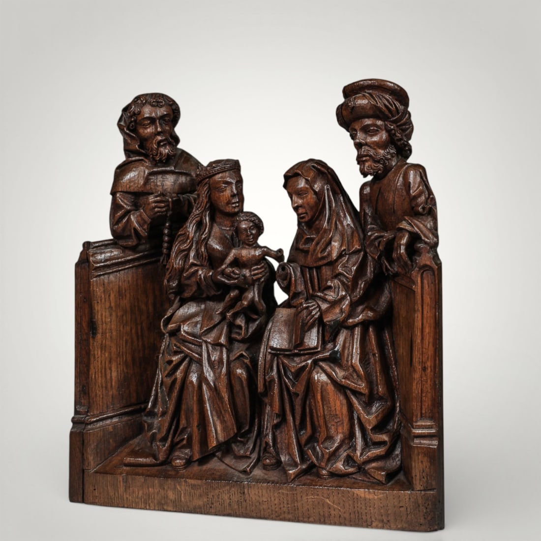 Group of the Virgin with Child and Saint Anne, Saint Francis and donor, Flemish School, 17th Century: Carved oak. Measures 50 x 47 cm. Sculptural group arranged in deep relief, organized into a devotional scene of marked narrative density, where the crowned Virgin holds the Child in the center of the
