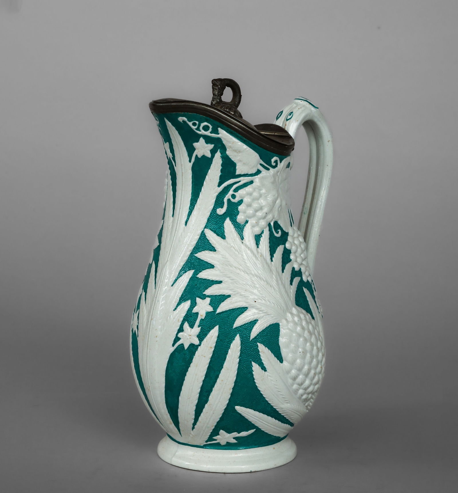 Verseuse with embossed vegetal decoration, English manufacture, 19th century: White glazed ceramic bisque with relief decoration and a tin lid. Measures 26 cm in height. This slightly stylized, globular pourer sits on a circular base, with a gently raised neck that culminates i