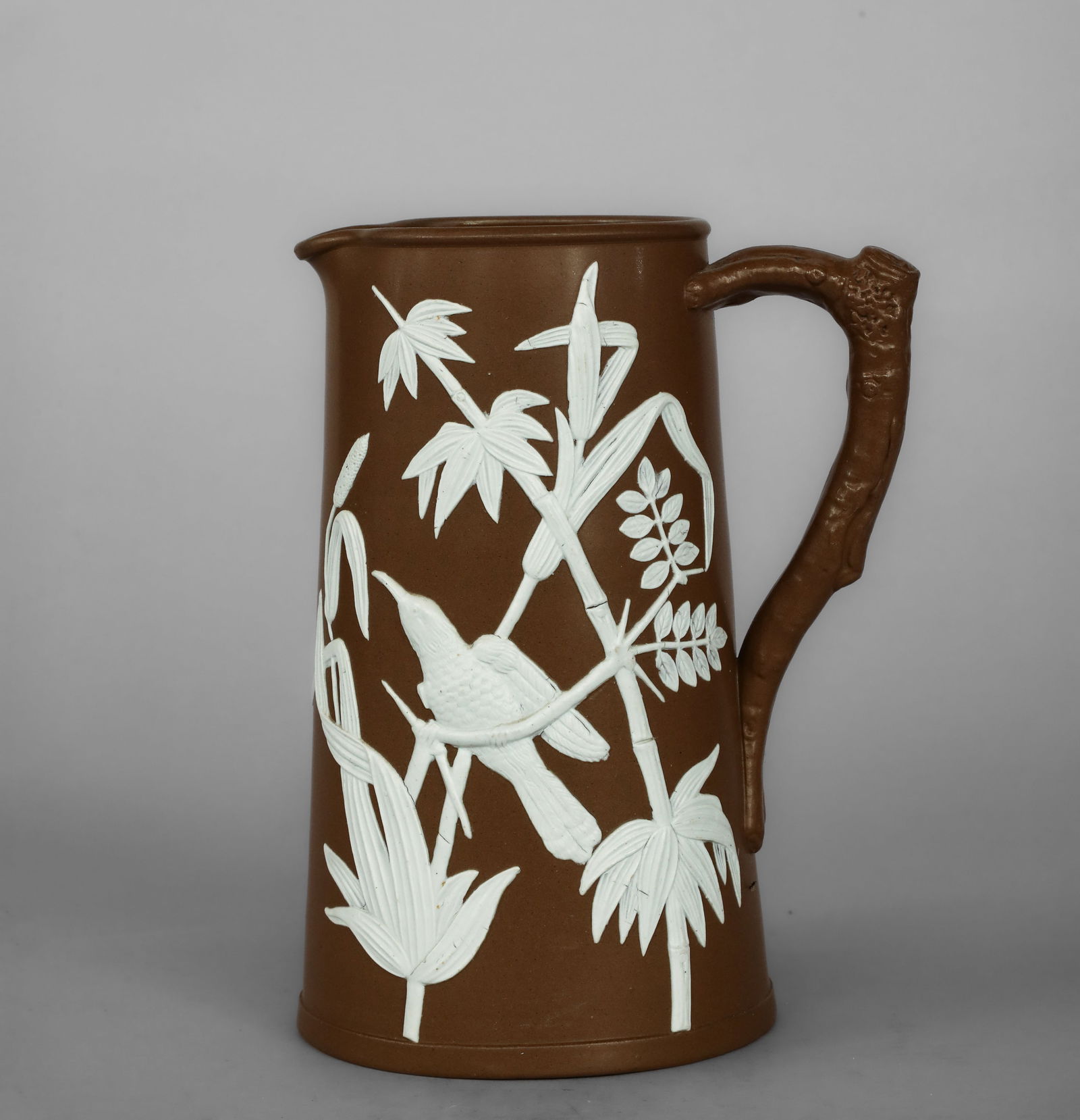 Verseuse with naturalistic decoration and kingfisher, English manufacture, 19th century: Brown glazed ceramic bisque with white relief decoration. Measures 19.5 x 9 cm. A slightly truncated conical pouring vessel, set on a circular base, with a spout integrated into the profile and a rear